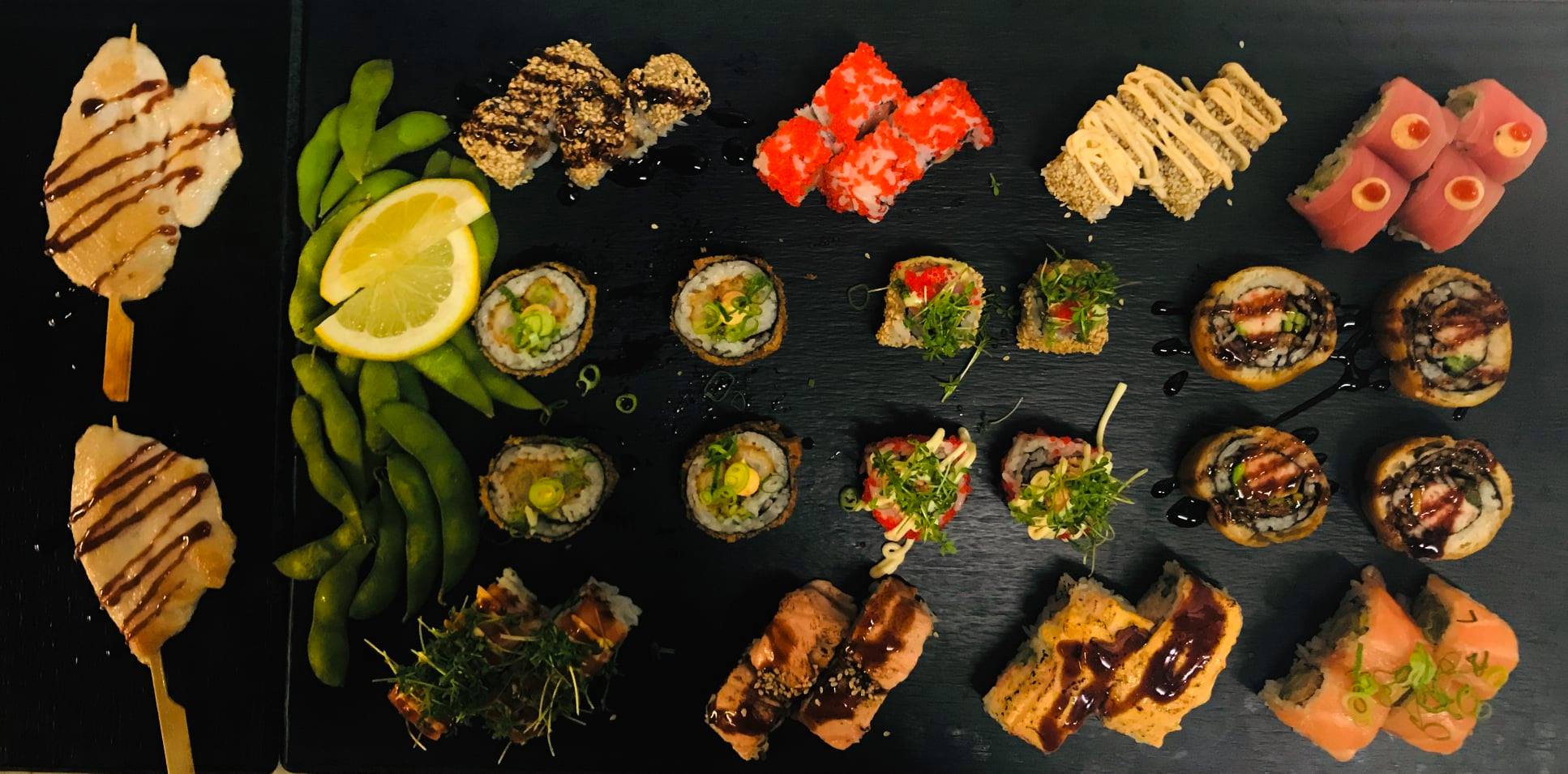 Sushi, edamame og kyllingespyd på sort fad hos Joci Sushi